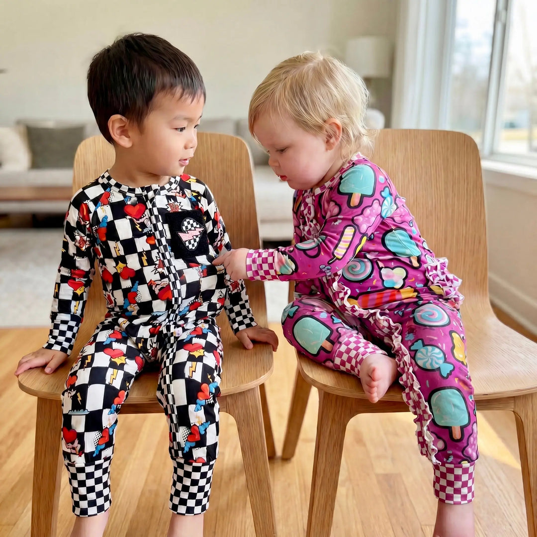 Two babies in 2 different convertible onesies sitting on a wooden chair